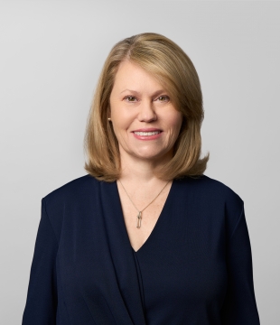 Woman with shoulder-length blonde hair wearing a black blouse smiles for a headshot.